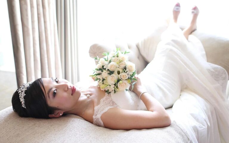 A bride reclining in a tiara, holding a cream rose bouquet, Four Seasons Park Lane, Elizabeth Hsieh Make Up Artist