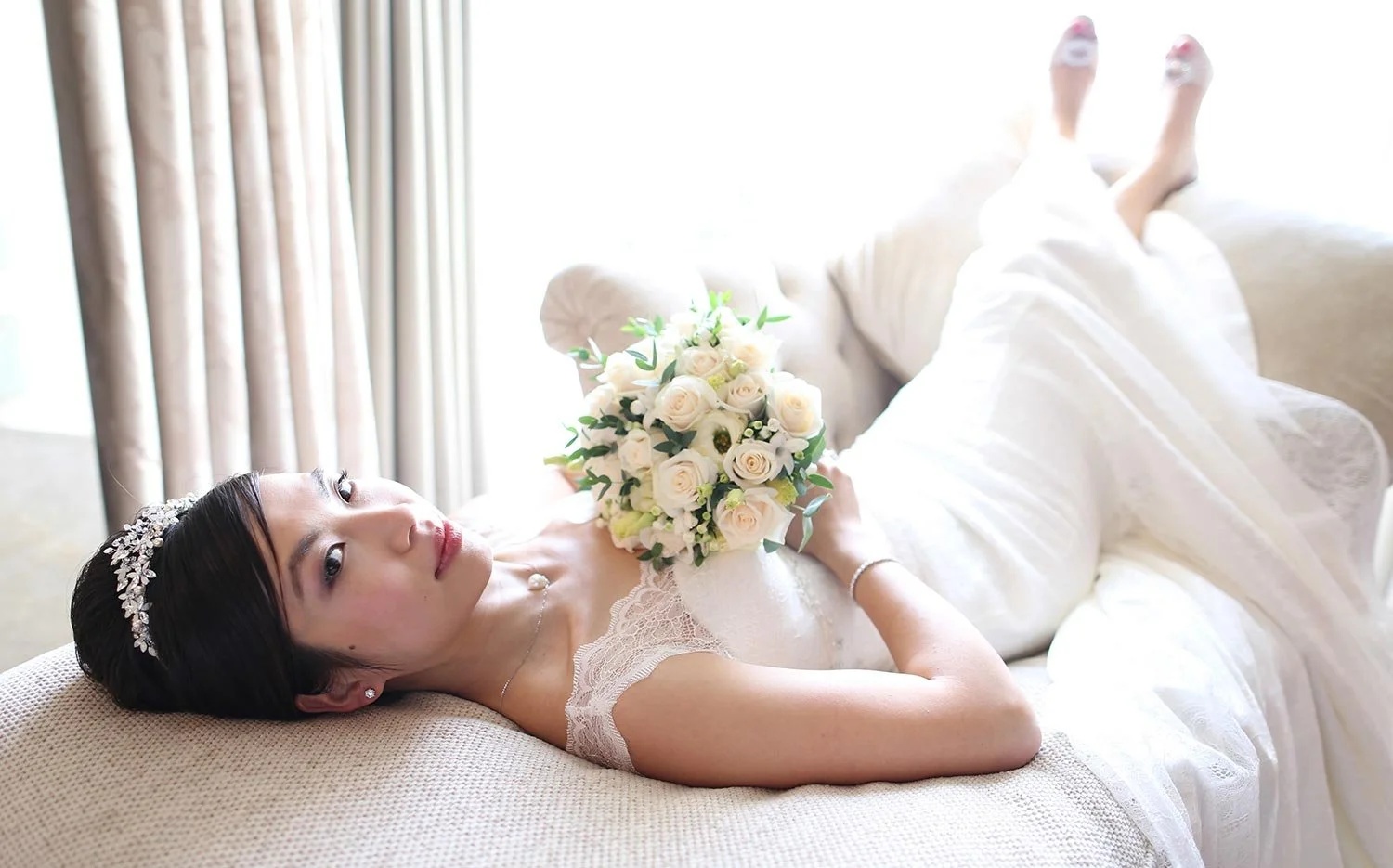 A bride reclining in a tiara, holding a cream rose bouquet, Four Seasons Park Lane, Elizabeth Hsieh Make Up Artist