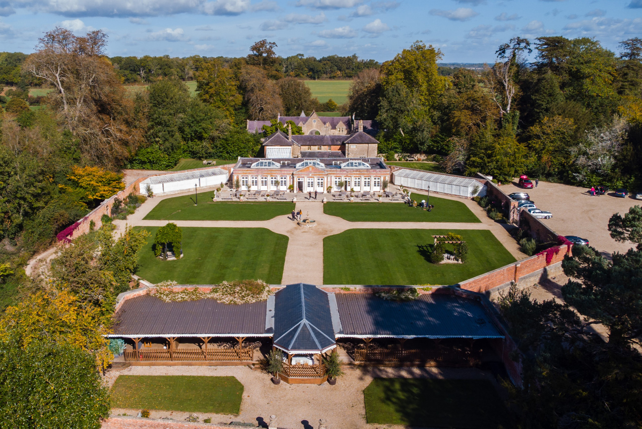 Aerial view of the Walled Garden, its lawns and paths, with the Orangery and glasshouses beyond and the Italian Garden veranda in the foreground, Elmhay Park