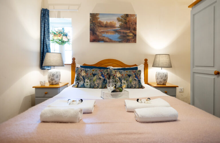 A double bed made up with towels in an Elmhay Village cottage, Elmhay Park