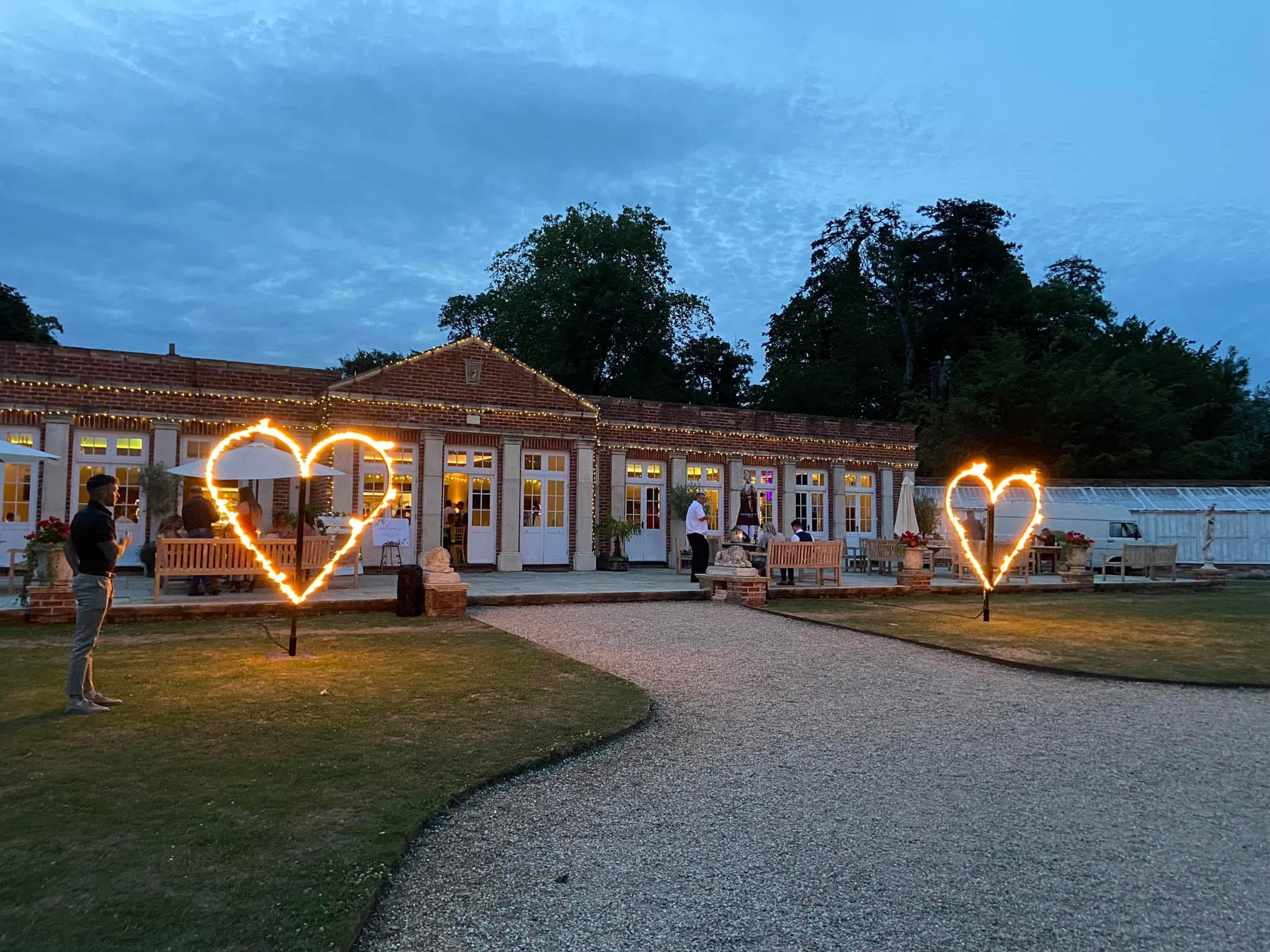 Illuminated heart frames on the lawn in front of the Orangery on a summer evening, Elmhay Park