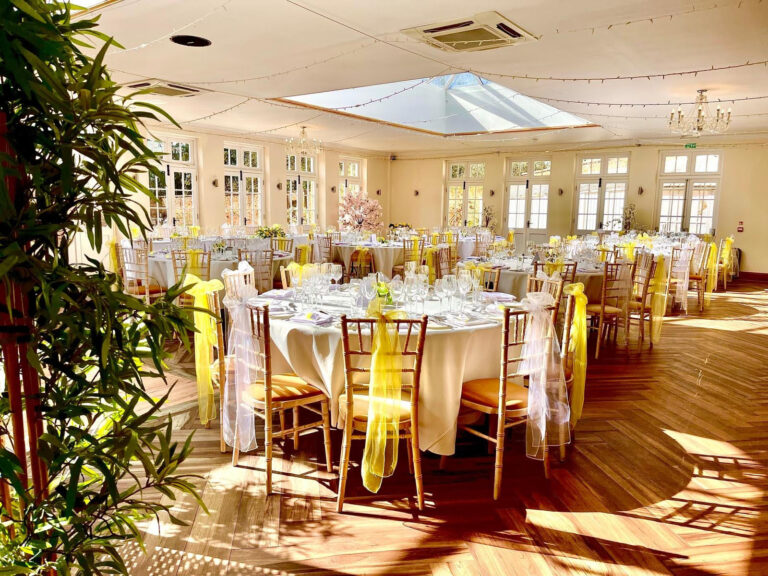 The Orangery set for dinner, with yellow chair sashes and late sun across the wooden floor, Elmhay Park