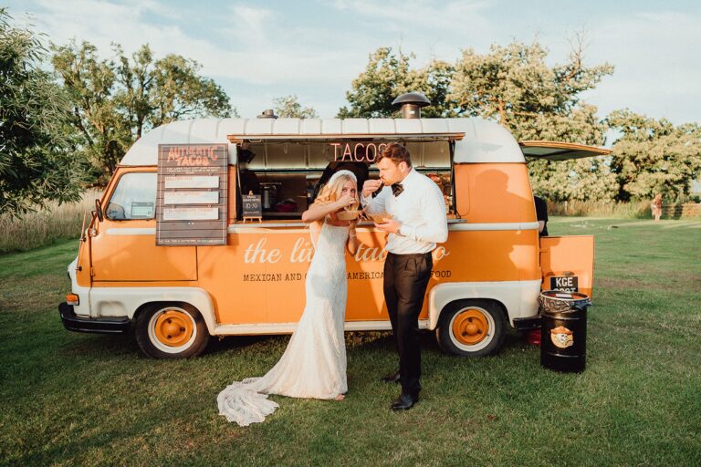 A couple beside an orange campervan on the lawn, Elmore Court