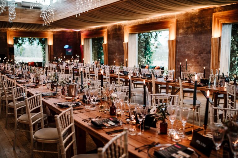 Long banquet tables in the timber-lined Gillyflower beneath festoon lights, Elmore Court