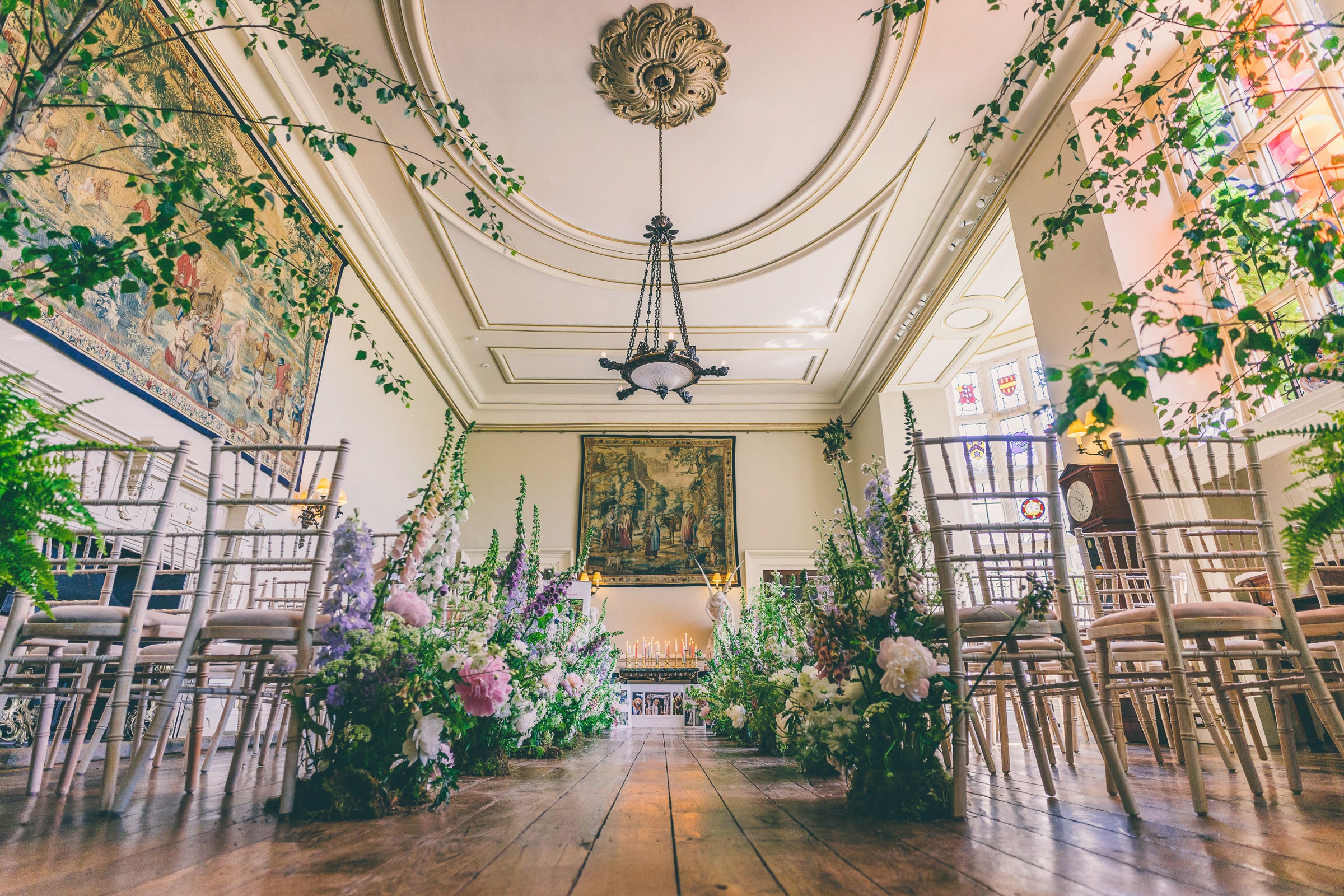 A grand room in the main house dressed for a wedding, foliage and florals climbing the walls, Elmore Court