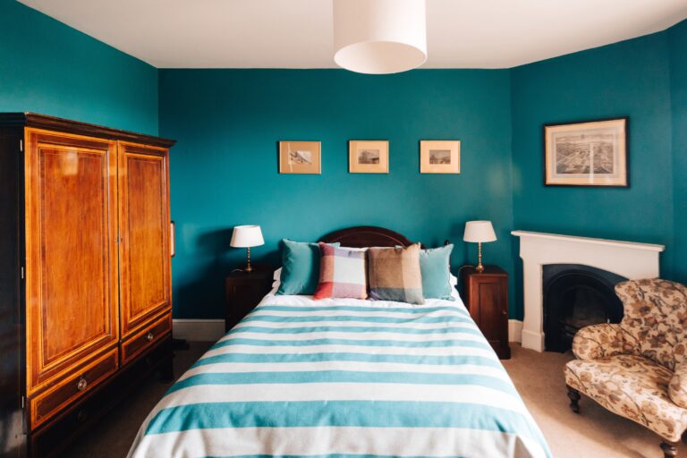 A teal-green bedroom with a striped bed, Elmore Court