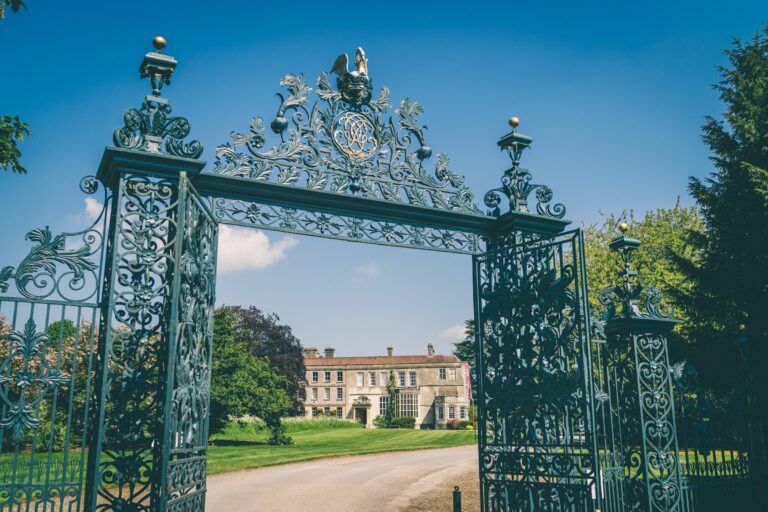 The ornate wrought-iron entrance gates, the house beyond, Elmore Court