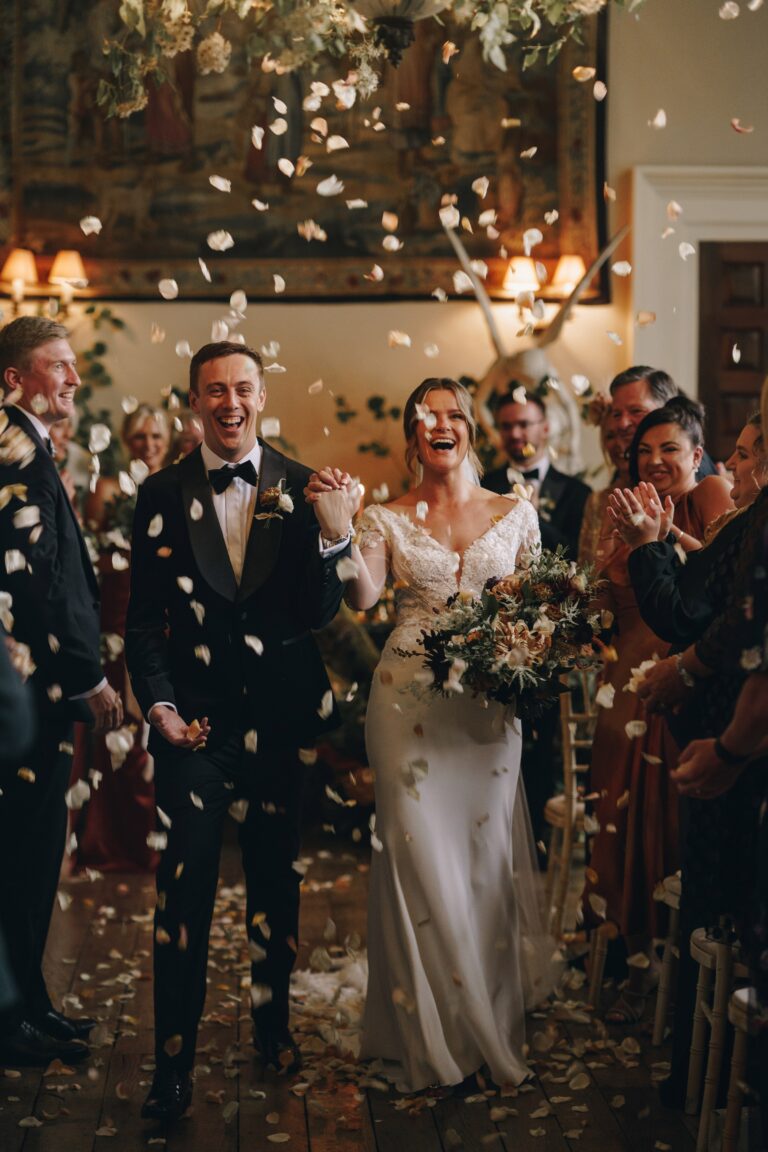 The couple leaving through a shower of confetti, guests lining the way, Elmore Court