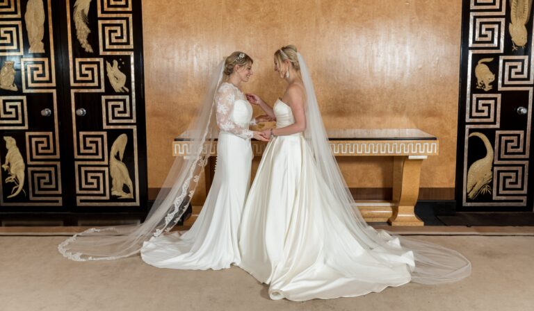 Two brides before the Art Deco marquetry of the Entrance Hall, their veils pooling across the floor, Eltham Palace