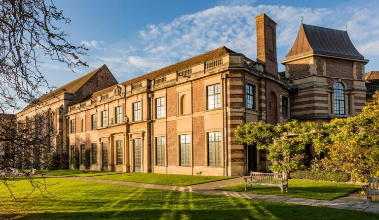 The Art Deco frontage of Eltham Palace in golden light, lawns and a garden bench before it, Eltham Palace