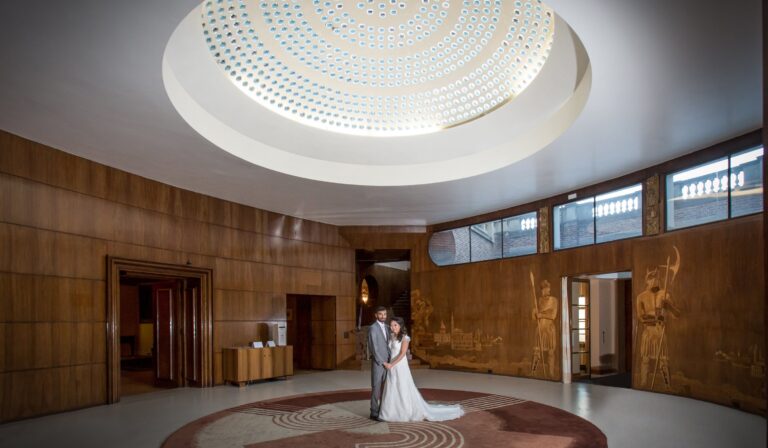 A couple embracing beneath the glass-and-concrete dome of the Art Deco Entrance Hall, Eltham Palace