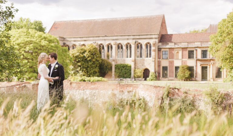 A couple in the meadow, the medieval Great Hall and moat wall rising behind, Eltham Palace