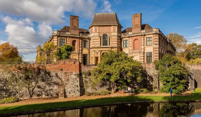 Eltham Palace and its medieval Great Hall across the moat in autumn, the fifteenth-century bridge to one side, Eltham Palace