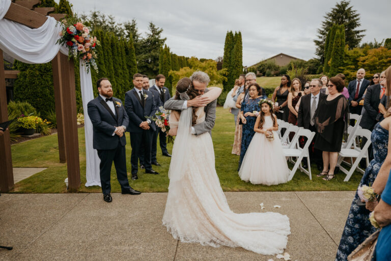 Bride turning in the aisle of a garden ceremony as guests look on, Emett Joseph Photography