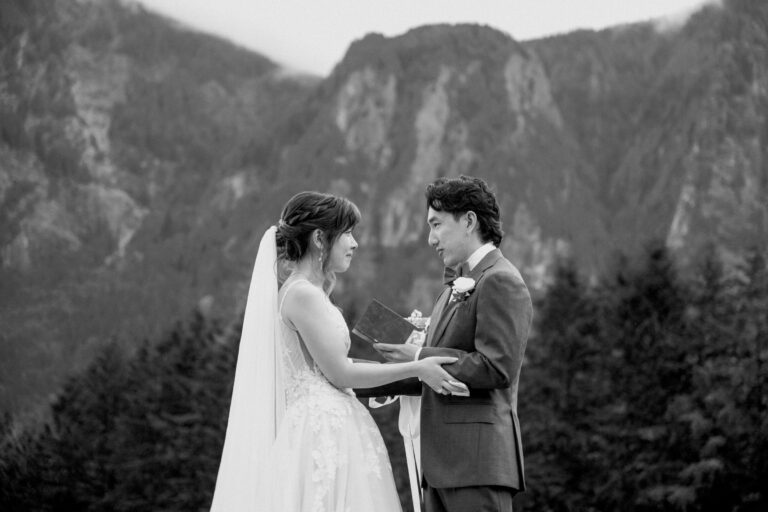 Bride and groom holding hands beneath a mountain ridge, in black and white, Emett Joseph Photography