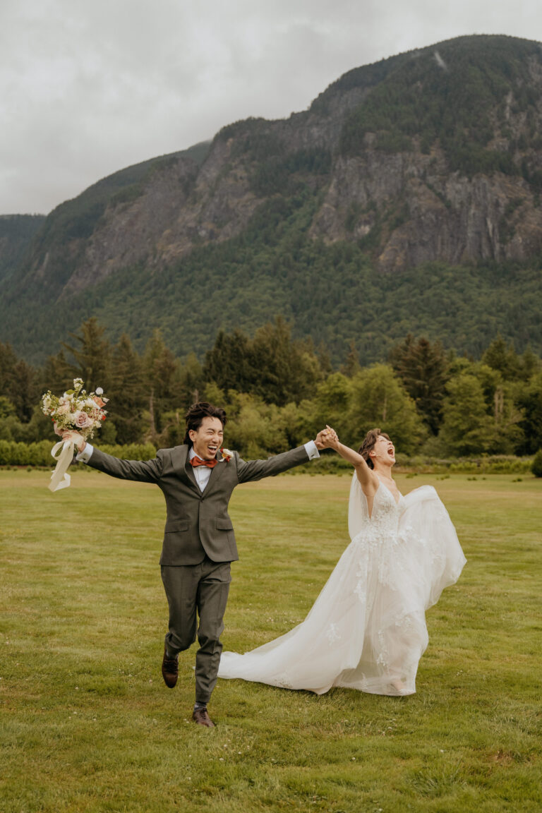 Couple on a wide lawn, the bride's train in the air, with a mountain behind, Emett Joseph Photography