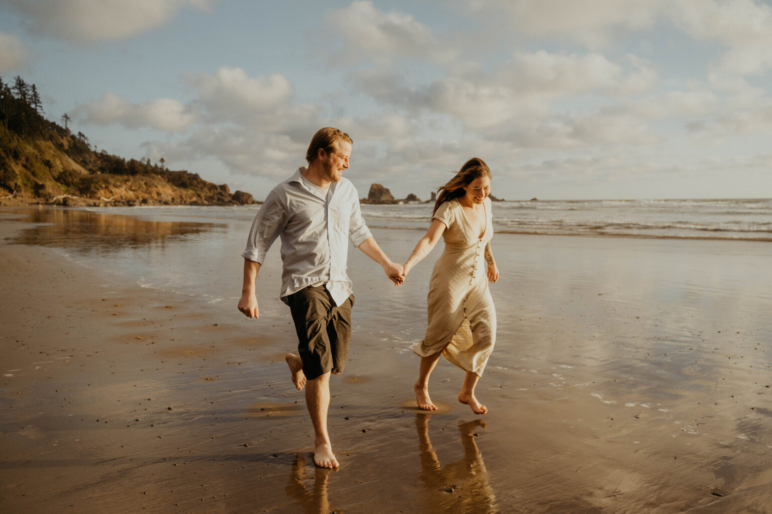 A couple walking hand in hand along the sand at Cannon Beach, Oregon