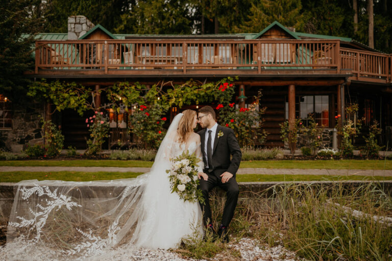 Couple kissing in front of a timber lodge among planted flowers, Emett Joseph Photography