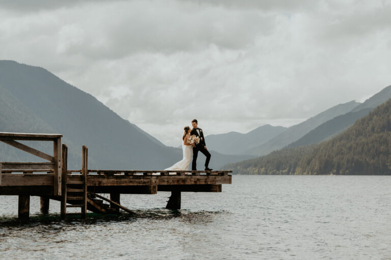Couple on a lake pier beneath mountains, Olympic National Park elopement, Emett Joseph Photography