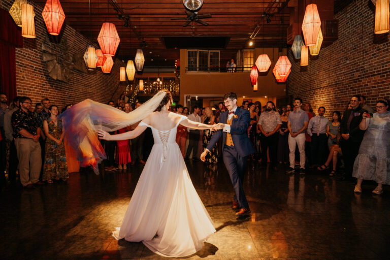 First dance in a hall hung with paper lanterns, the bride's veil in motion, Emett Joseph Photography