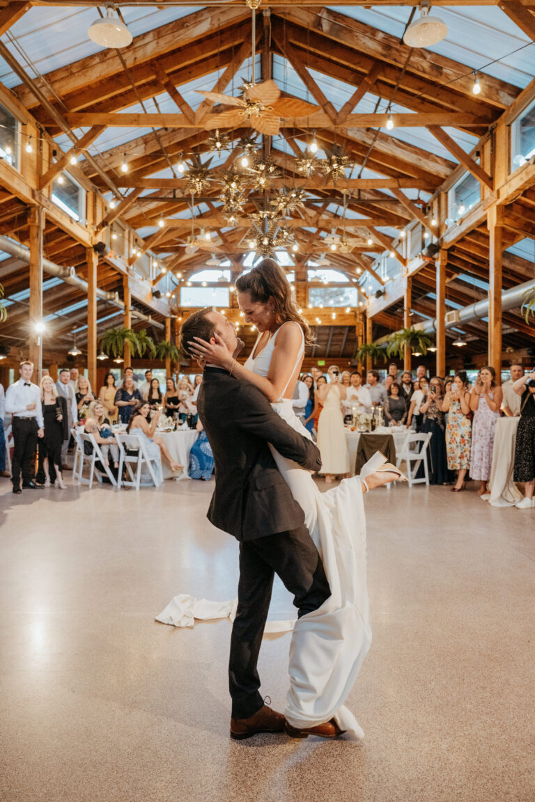 Couple dancing in a timber-roofed hall at Kiana Lodge, guests behind, Emett Joseph Photography