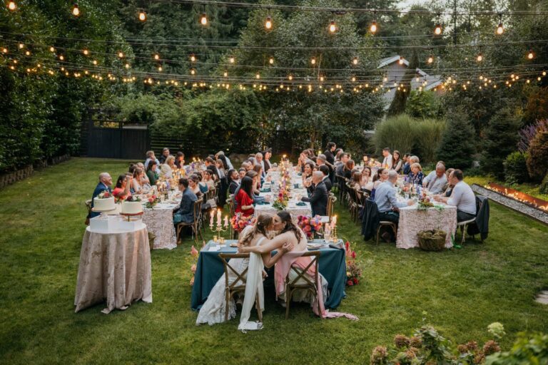 Guests seated at round tables on a lawn under string lights, Emett Joseph Photography