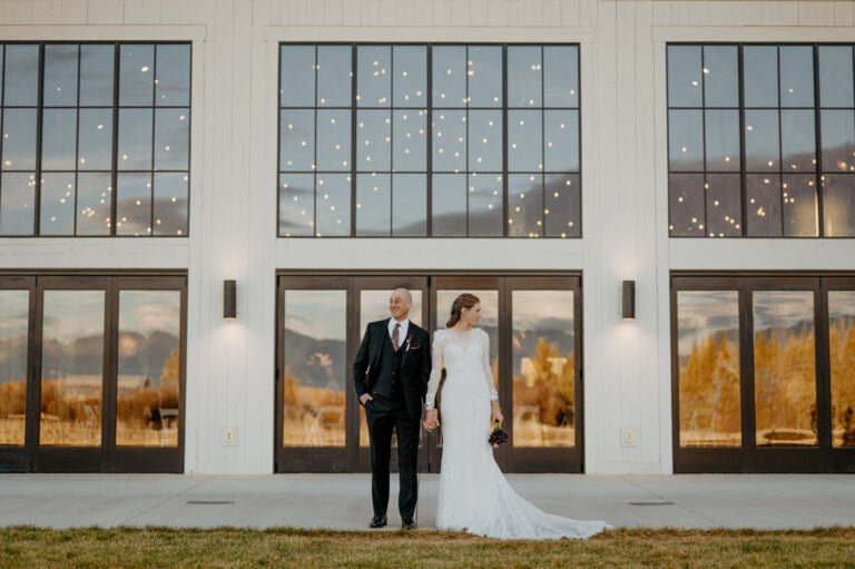 Couple in front of a white building with tall black-framed windows, Emett Joseph Photography