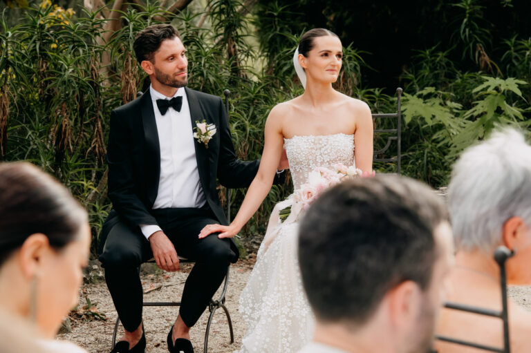 The couple seated during their ceremony in a garden in the South of France, family and friends looking on, Emma-Jane Photography