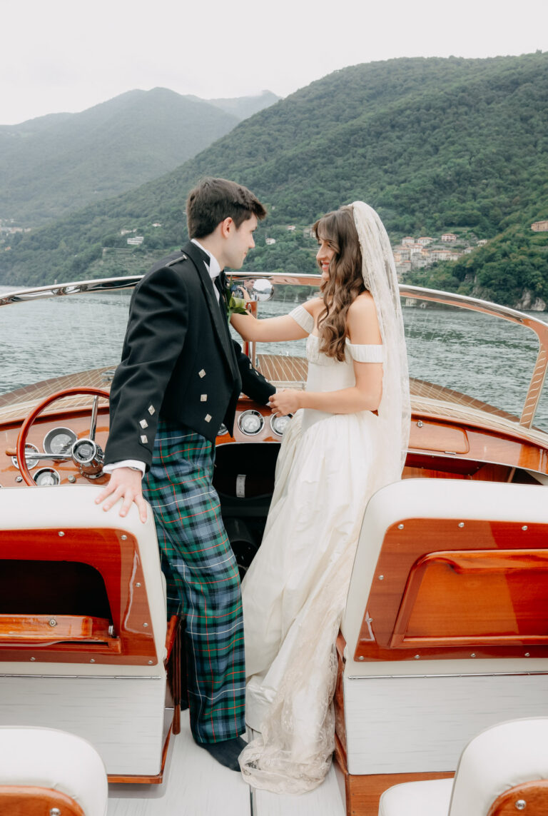 A couple on a wooden motor launch on Lake Como, on their wedding day at Villa Regina Teodolina, Emma-Jane Photography