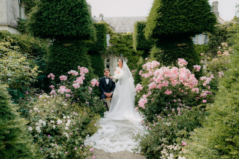 A bride and groom among the roses and clipped yew of the gardens at Euridge Manor, Emma-Jane Photography