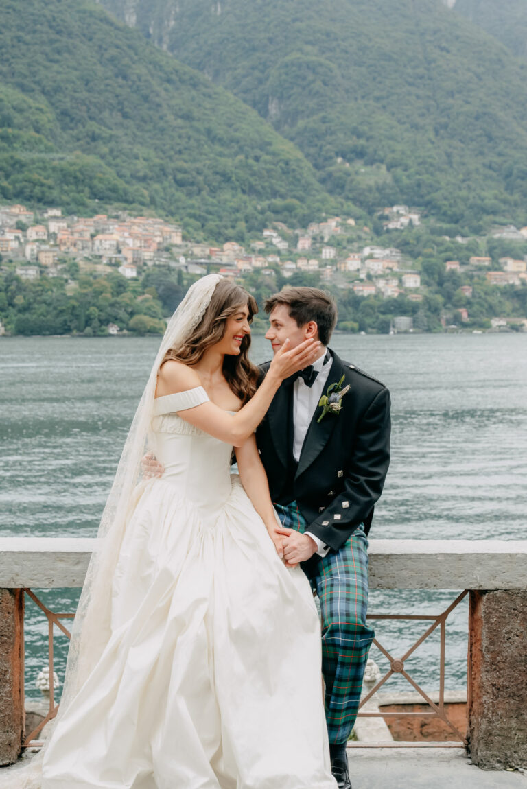A couple on a lakeside terrace at Villa Regina Teodolina, Lake Como, the shore villages behind, Emma-Jane Photography