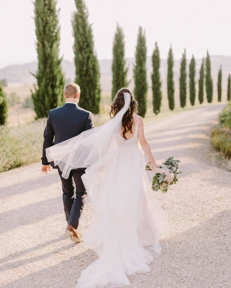 A couple walking along a gravel drive lined with cypresses in Tuscany, Enjoy Tour Tuscany