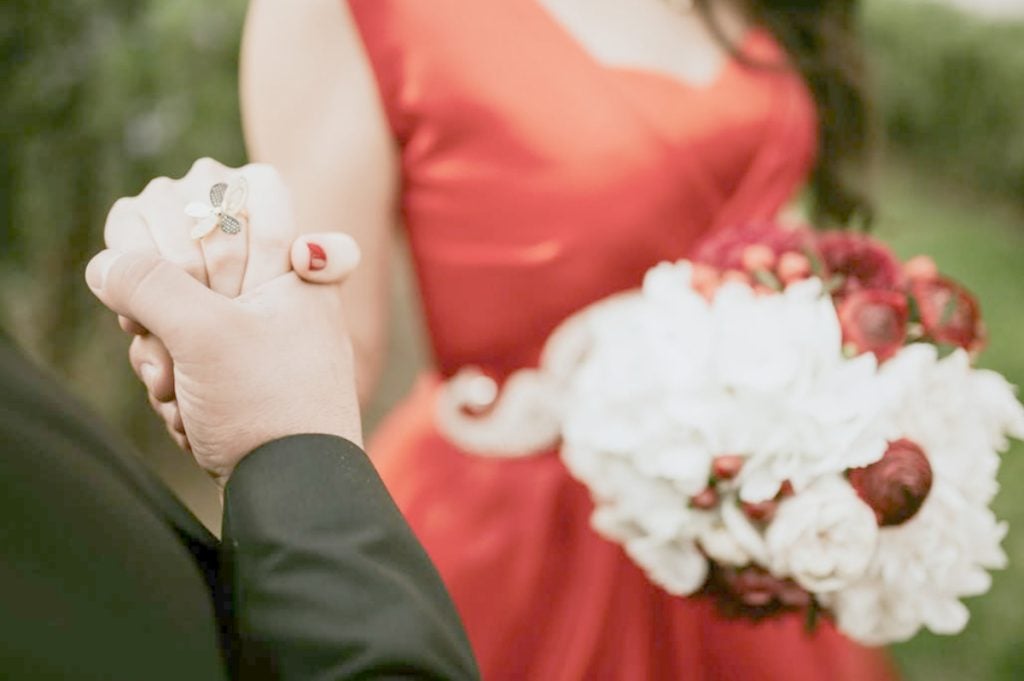 Clasped hands and a white and red bridal bouquet, Enjoy Tour Tuscany