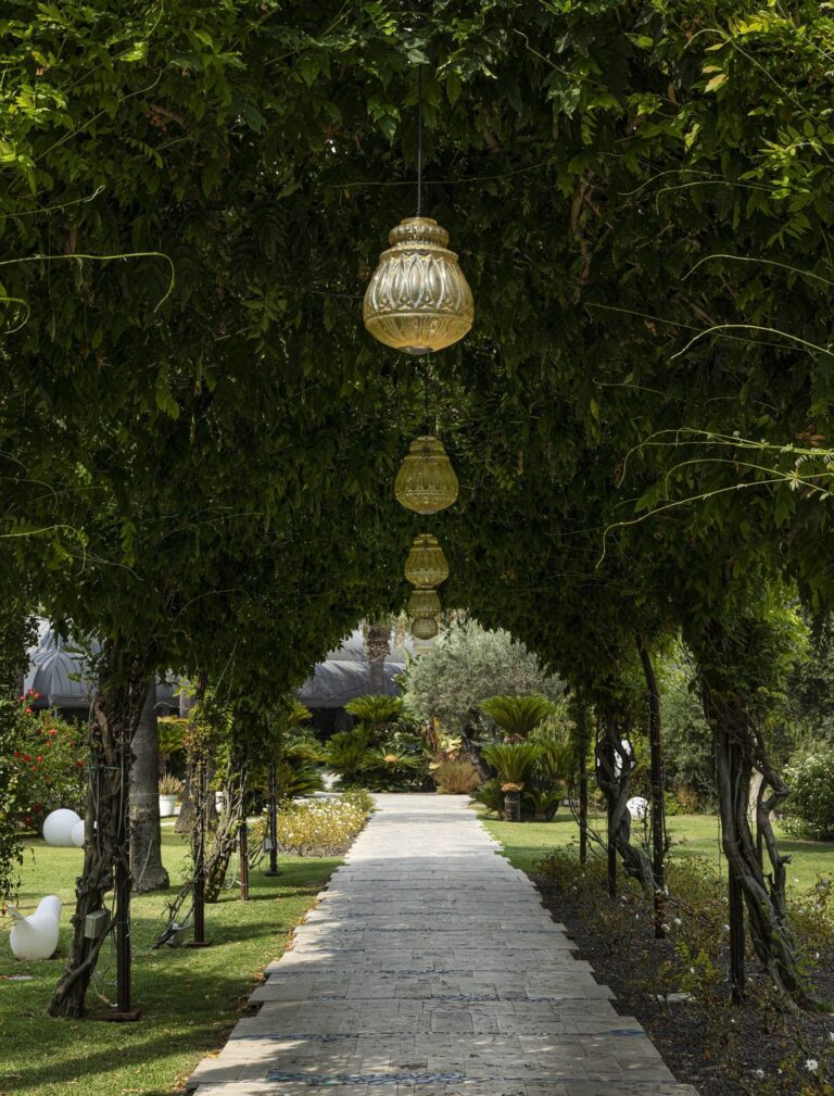 A lit garden pergola walk at night, Esplanade Boutique Hotel