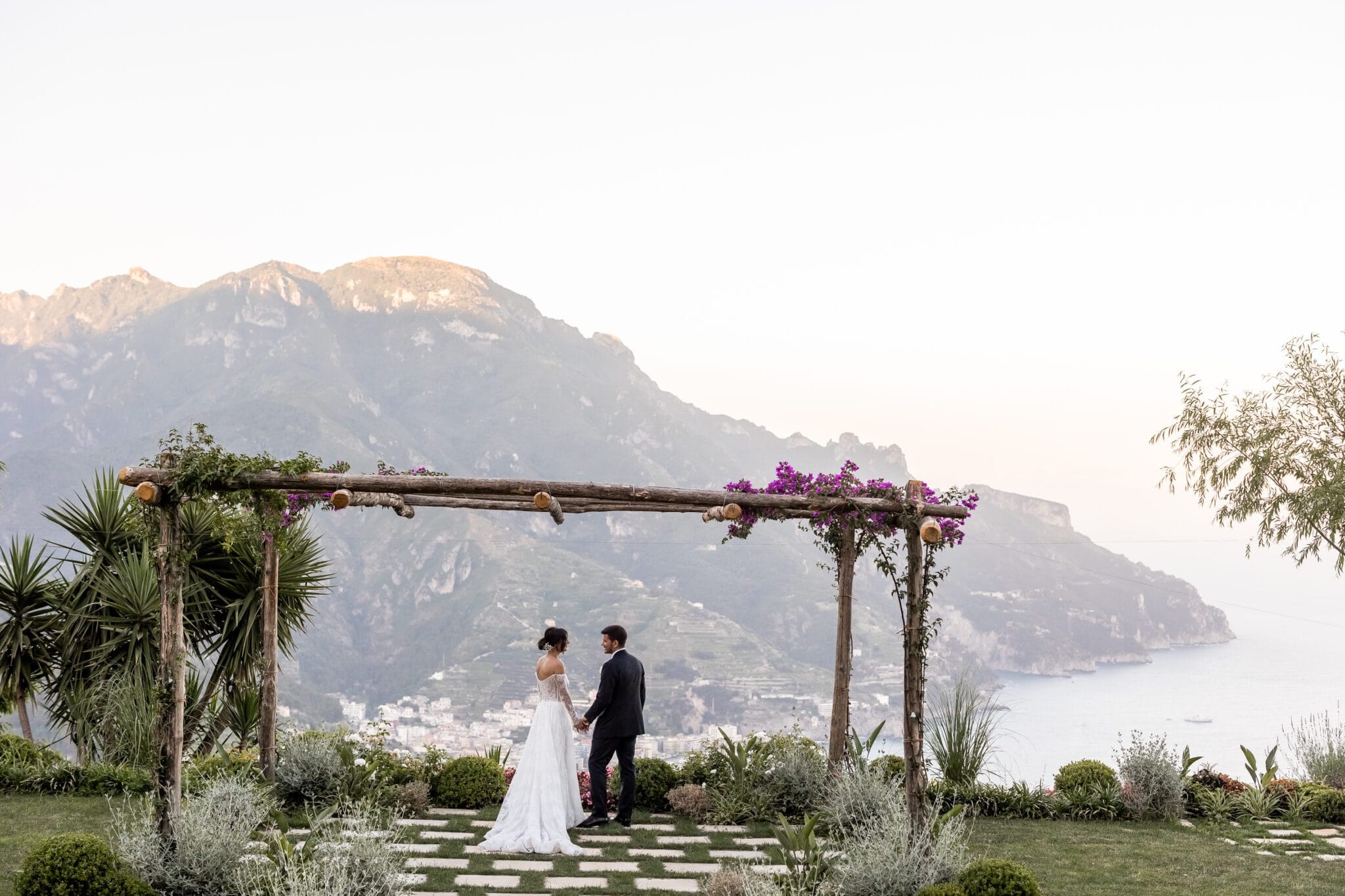 A pergola on a clifftop terrace, the coast and the sea below at dusk, Ester Chianelli Weddings & Events