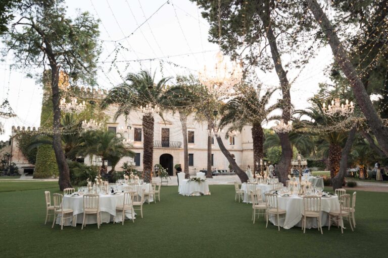 A castellated palazzo across its lawn, tables laid among the palms, Ester Chianelli Weddings & Events