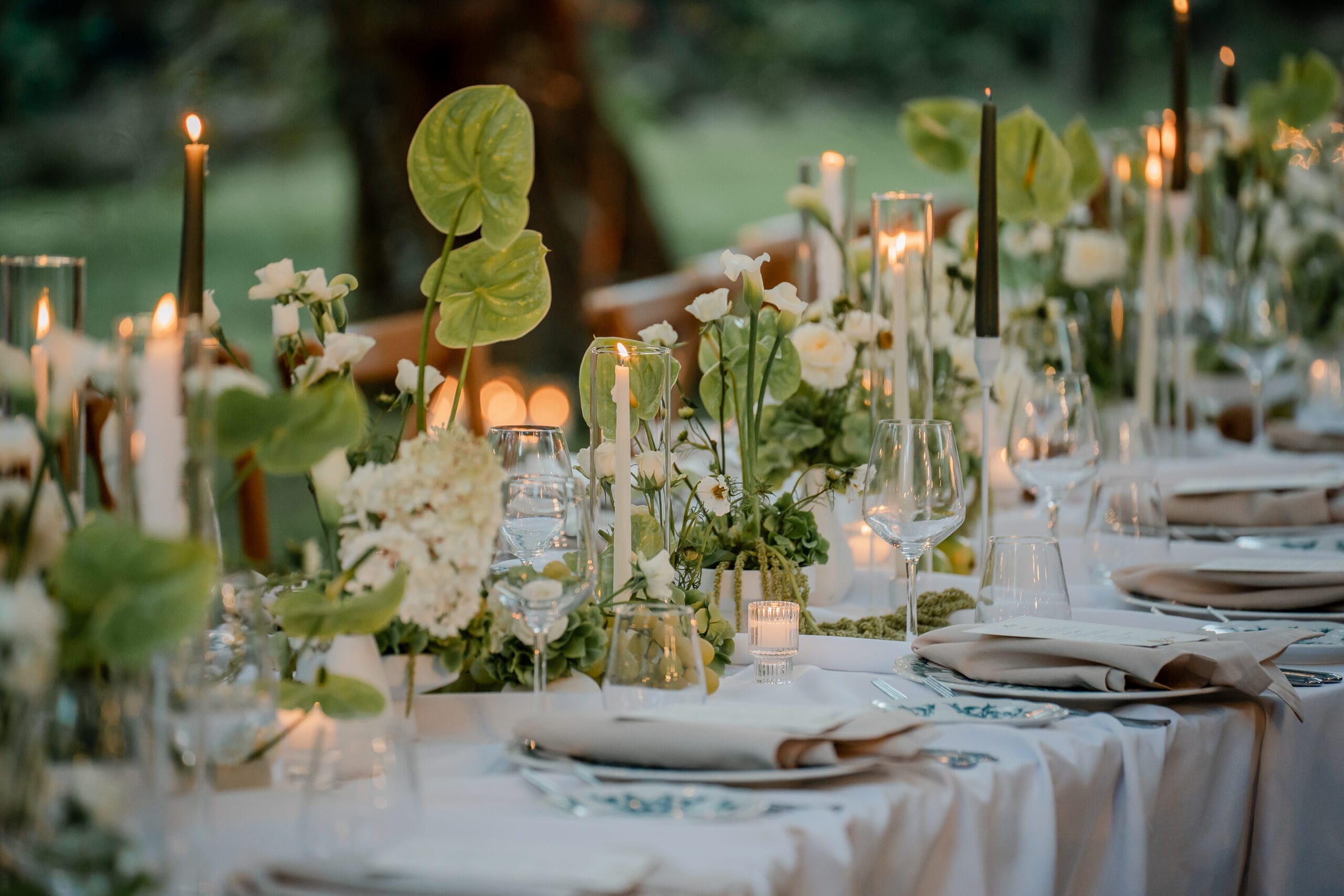 Green anthuriums and tapers down a table laid under the trees, Ester Chianelli Weddings & Events