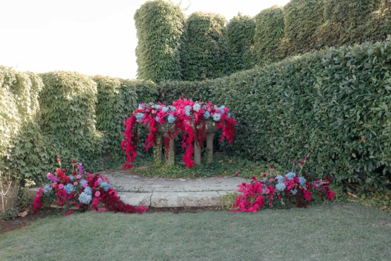 Outdoor ceremony at Castello di Torre Alfina, red, pink and blue flowers framed by a clipped hedge, Eventilab Weddings