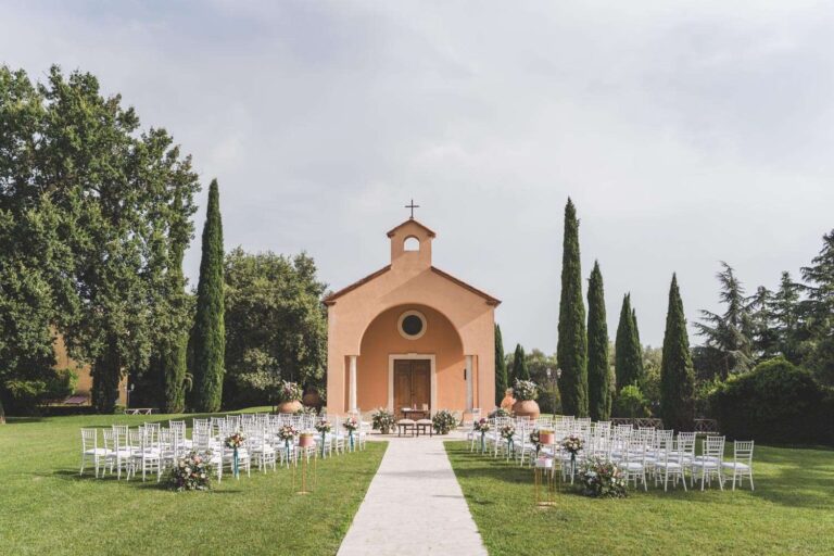 Ceremony set-up on the lawn in front of the chapel at Scuderie San Giorgio, Rome, between cypress trees, Eventilab Weddings