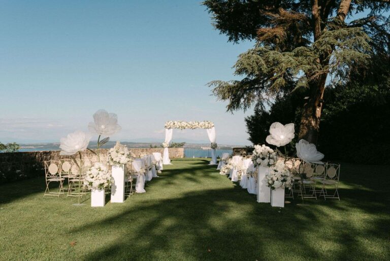 Ceremony set-up in the garden at the Castello di Bracciano with oversized white paper flowers and the lake beyond, Eventilab Weddings