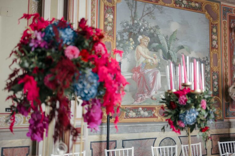 A tall centrepiece of red amaranthus, roses and hydrangea in a frescoed room at Torre Alfina, Eventilab Weddings