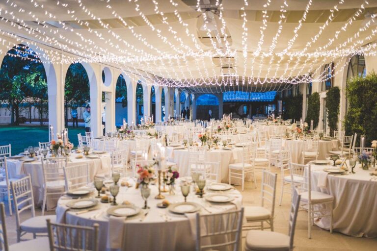 Reception under a canopy of string lights at Scuderie San Giorgio, mixed garden flowers on white tables, Eventilab Weddings