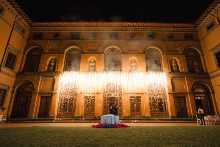 A curtain of cold sparks across the courtyard facade of Castello di Torre Alfina at night, Eventilab Weddings
