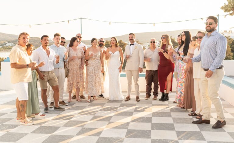 A wedding party gathered on a chequered terrace for a group photograph in Milos, Eventuries Wedding Planning and Styling