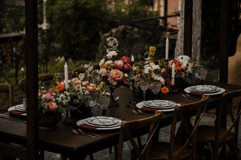 A long dark table set with candles and low arrangements of orange and peach flowers, for an elopement in Crete, Eventuries Wedding Planning and Styling