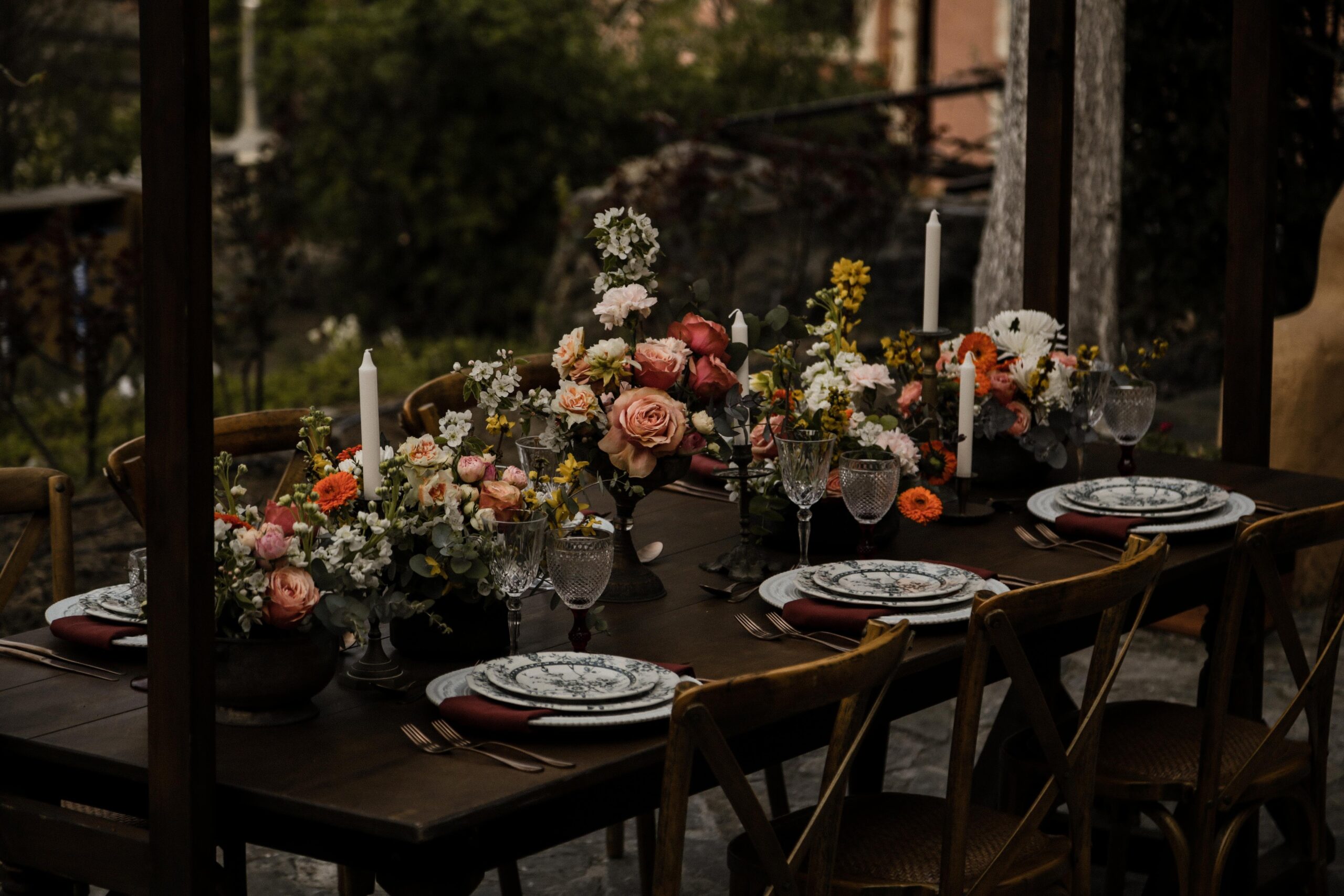 A long dark table set with candles and low arrangements of orange and peach flowers, for an elopement in Crete, Eventuries Wedding Planning and Styling