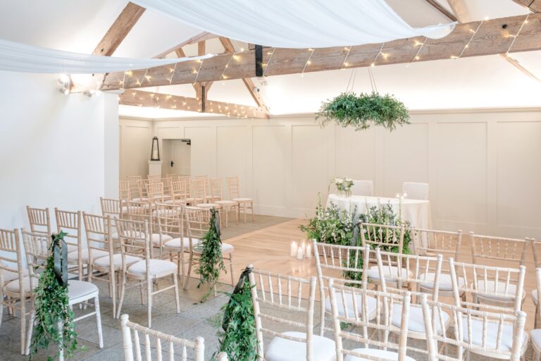 The Meadow Barn from the side, with panelled walls, exposed oak trusses and chairs set for a ceremony, Farbridge