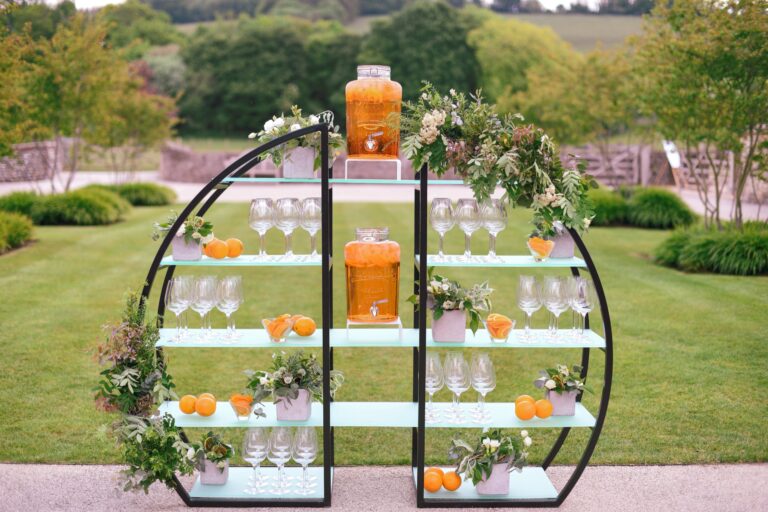 A drinks station of glasses, oranges and dispensers set on the lawn, Farbridge