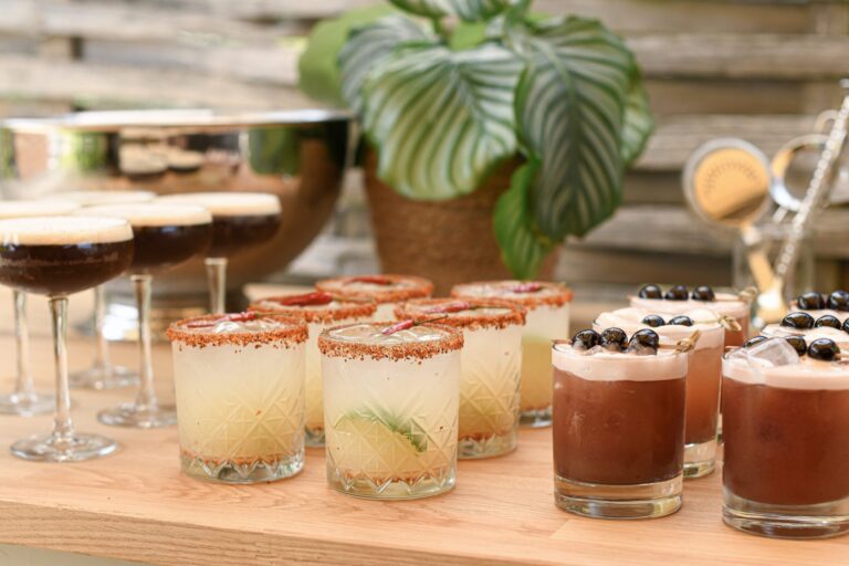 Cocktails lined up on a wooden bar, including espresso martinis and salt-rimmed tumblers, Farbridge
