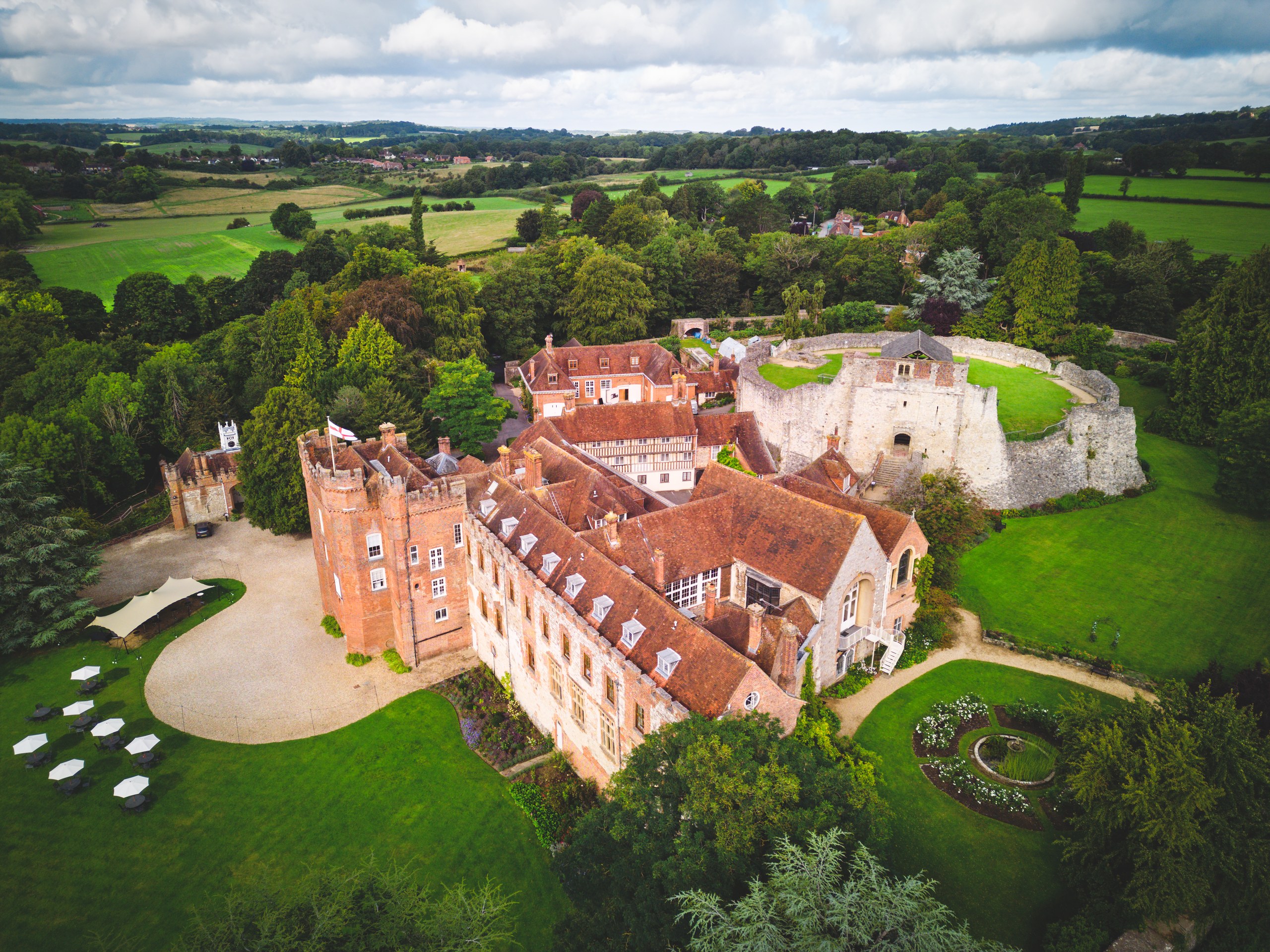 Aerial view of the Bishop's Palace, the round Norman Keep behind it and the gravel sweep and Great Lawn, with the Surrey countryside beyond, Farnham Castle